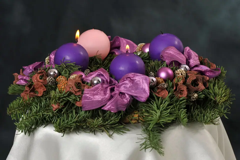 Advent wreath of evergreen branches with three violet candles and one rose candle, two of them lit